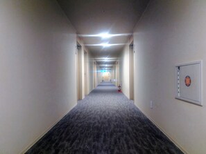A long, narrow hotel corridor with carpeted floors, doors on both sides, and overhead lighting. - New Grand Hotel Shinjo (Shinjo)