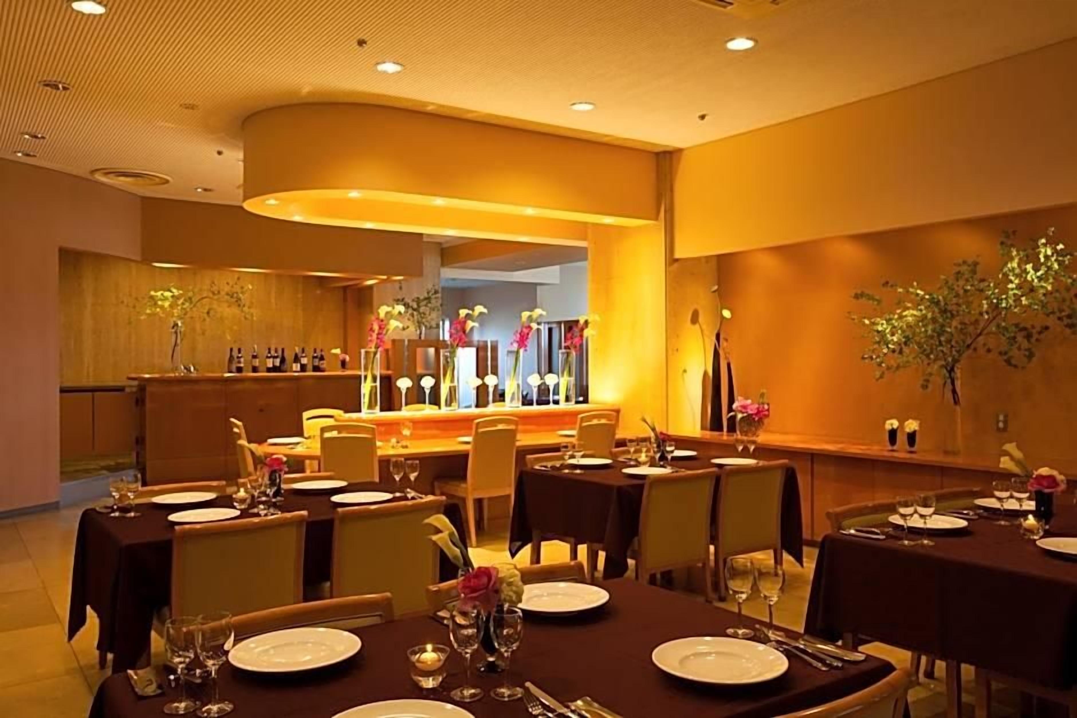 A restaurant with tables set for dining, a bar area, and a reception desk.