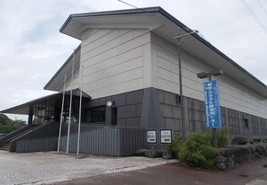 A modern building with a sloped roof, a staircase leading to the entrance, and a blue sign with Japanese text. - New Grand Hotel (Shinjo)