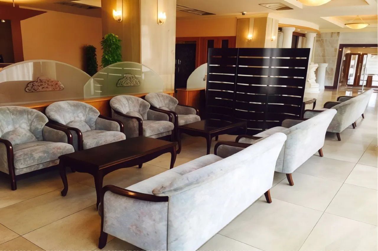 A hotel lobby with seating arrangements, a reception desk, and a decorative wall.
