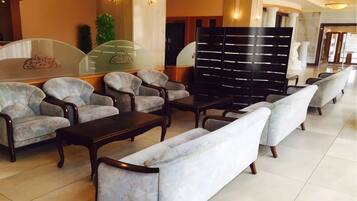 A hotel lobby with seating arrangements, a reception desk, and a decorative wall.