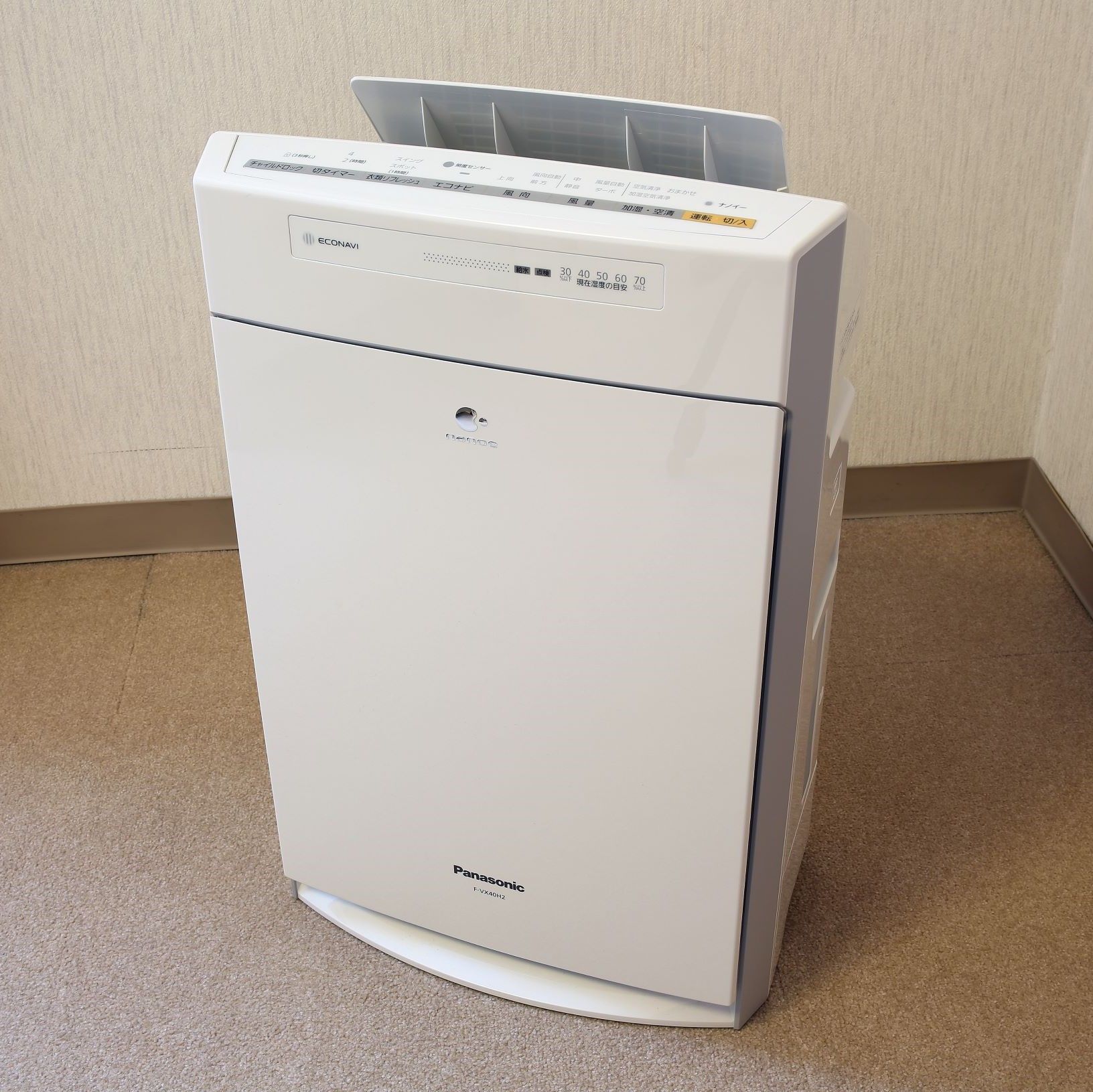 A white Panasonic F-VX40H2 air purifier in a corner with a beige carpet.