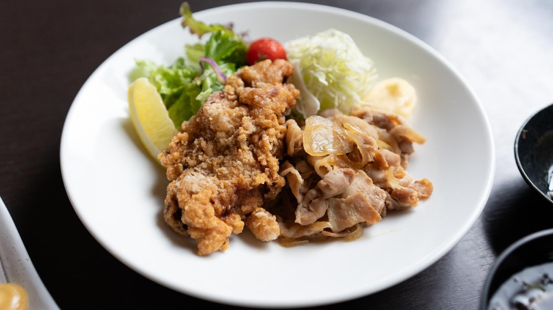 Une assiette blanche contenant du poulet frit, du chou et une tranche de citron.