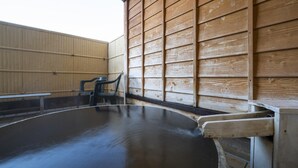 A swimming pool with a wooden deck and a bench. - Hotel Monzen No Yu (Joetsu)
