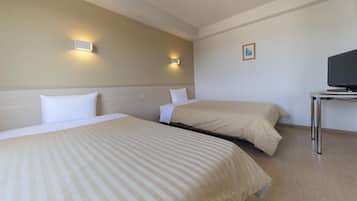 Quarto de hotel com duas camas, uma televisão sobre uma mesinha e duas luzes fixadas na parede.