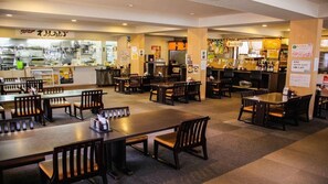 A restaurant with multiple tables and chairs, a kitchen area, and various signs and menus. - Hotel Monzen No Yu (Joetsu)