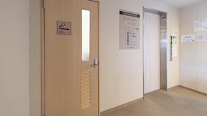 A hotel hallway with a wooden door, a vertical sign with room numbers, and a bulletin board with various notices. - Hotel Monzen No Yu (Joetsu)