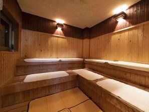 Eine Holzsauna mit Bänken und Sitzgelegenheiten mit weißen Kissen.