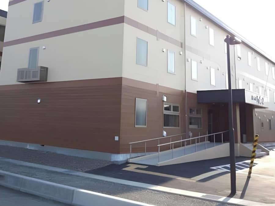A multi-story building with a flat roof, a ramp leading to the entrance, and a streetlight.