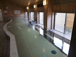 Una piscina con suelo de baldosas y bancos a los lados.