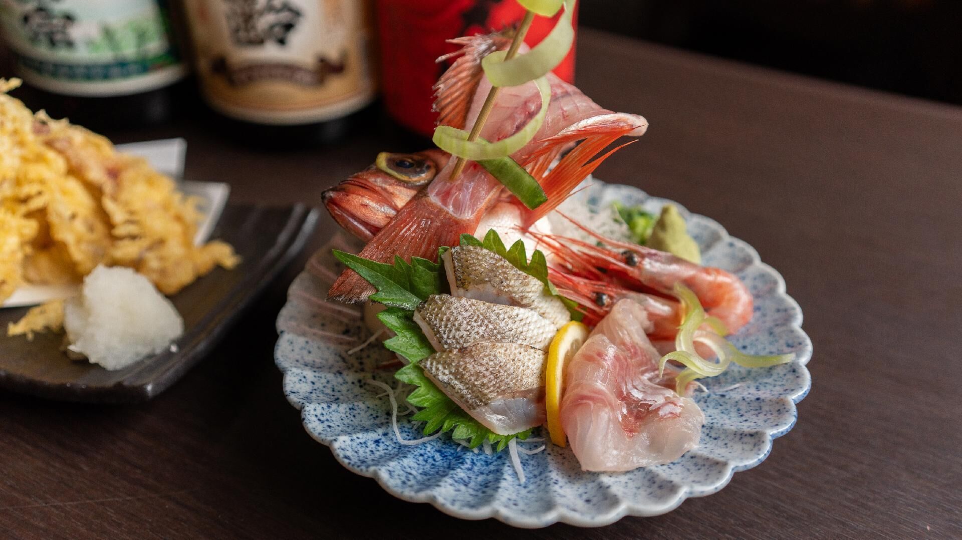 A seafood dish with shrimp, fish, and garnishes on a ceramic plate.
