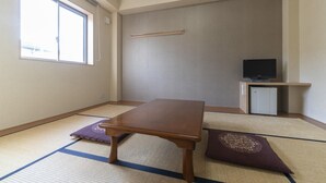 A room with tatami flooring, a wooden table, a television, and a small cabinet. - Hotel Monzen No Yu (Joetsu)