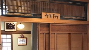 Une pièce de style japonais traditionnel, avec un sol recouvert de tatamis, une basse table en bois, un banc et une porte coulissante dotée de panneaux en verre dépoli.