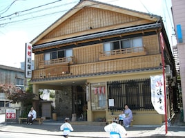 Un edificio tradicional japonés con fachada de madera, base de piedra y un letrero.