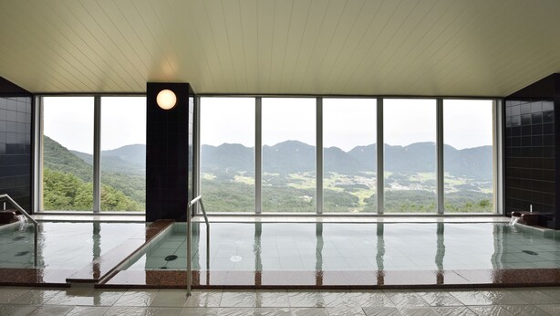 A spa area with a view of mountains, a large window, and a water feature. - Ikoinomura Shimane (Onan)