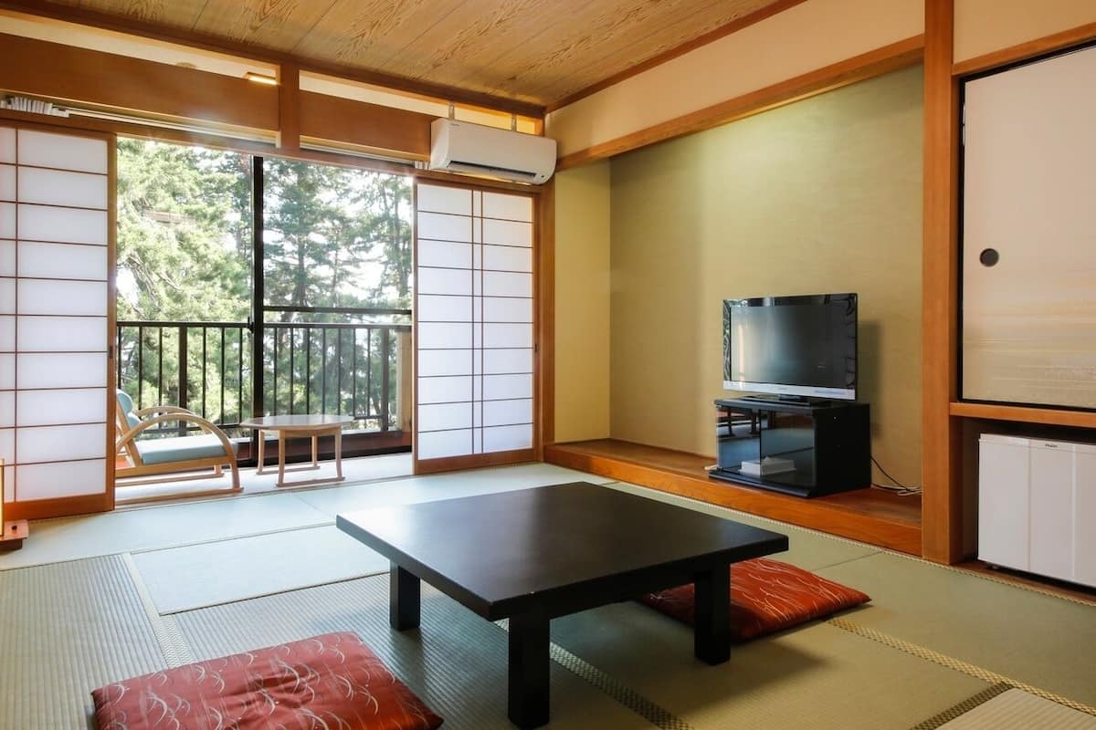 A traditional Japanese room with tatami flooring, a low table, a television, and sliding doors.