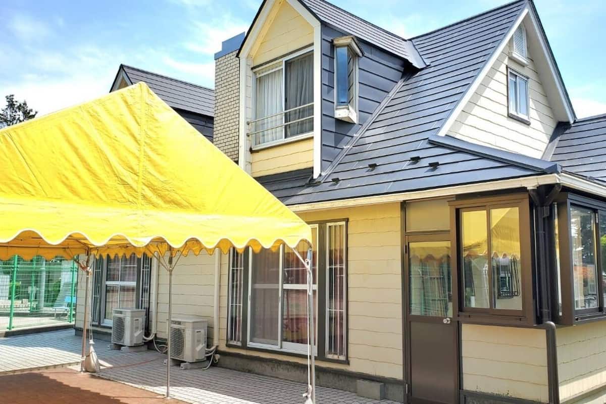A residential house with a covered patio, large windows, and a sloped roof.