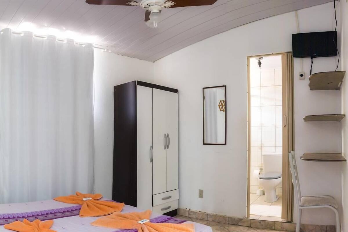 A hotel room with a bed, a wardrobe, a television, and a bathroom visible through an open door.