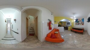 A spacious living area with a staircase, a dining table, and a sofa. - Pousada e Hostel Chapada Suítes (Lençóis)