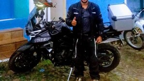 A person standing next to a motorcycle in front of a building with blue walls and a white door. - Pousada e Hostel Chapada Suítes (Lençóis)