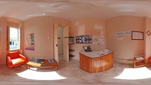 A reception area with a wooden desk, orange seating, and informational posters on the walls. - Pousada e Hostel Chapada Suítes (Lençóis)