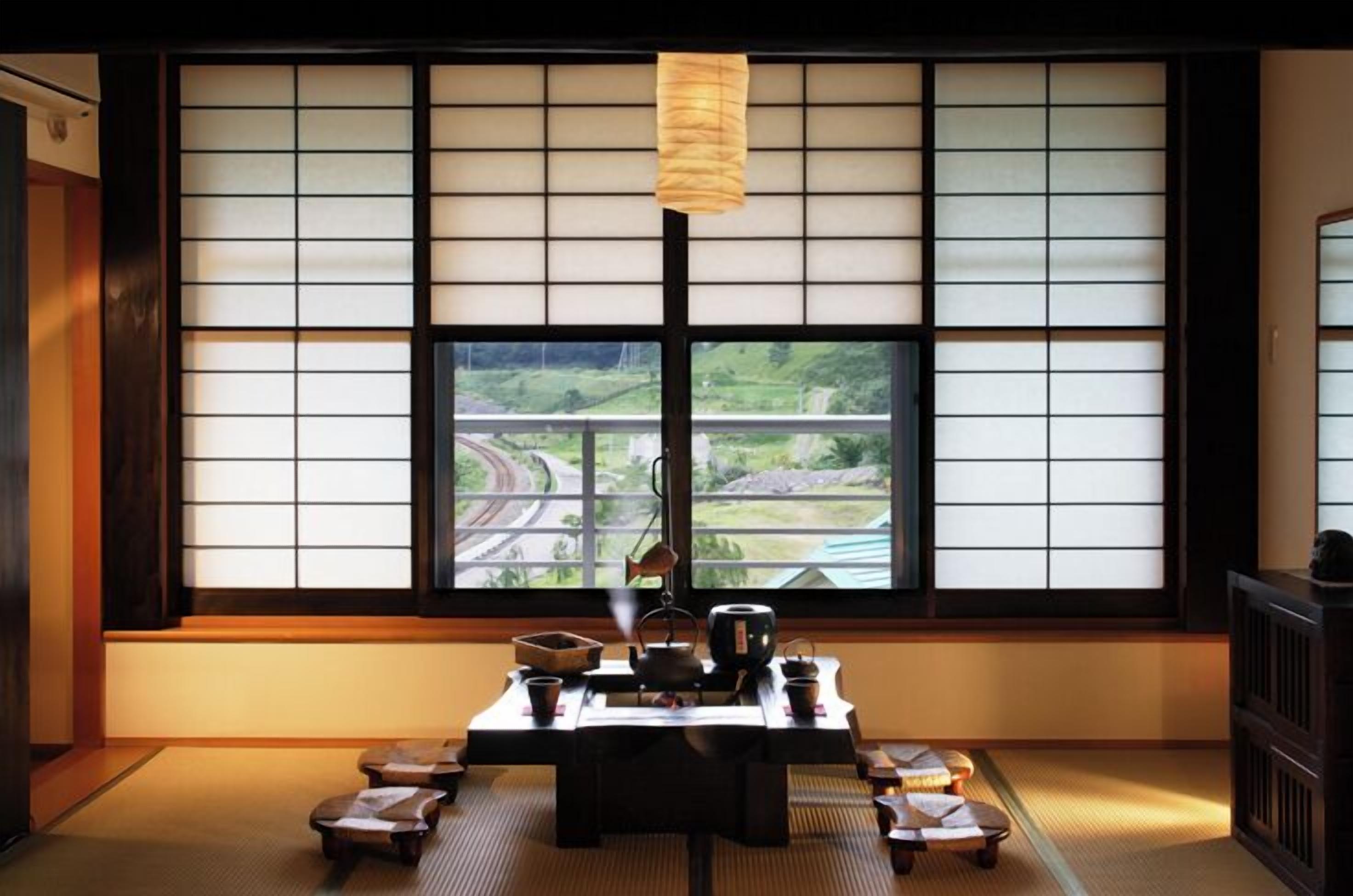 Een traditionele Japanse kamer met tatami vloerbedekking, een lage tafel met theeset en uitzicht op een snelweg door shoji schermen.