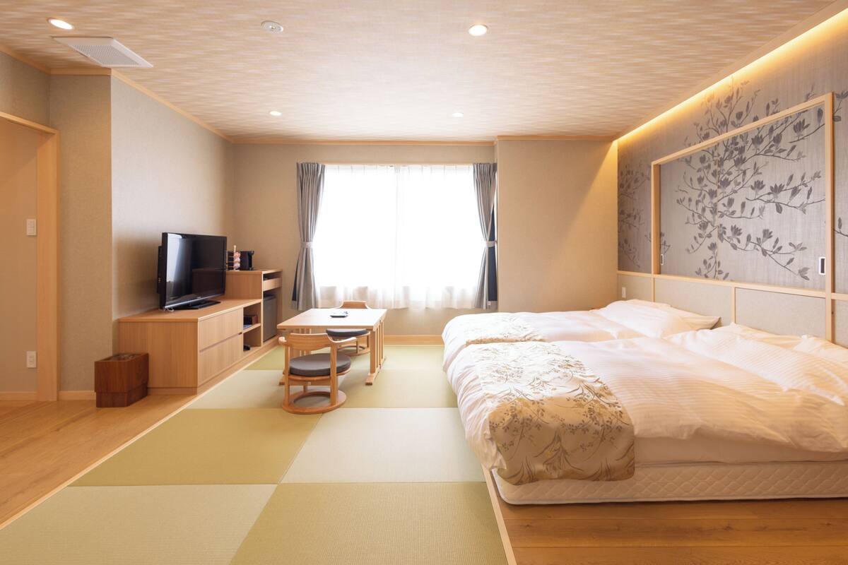 A room with a bed, a TV, a desk, and a chair.
