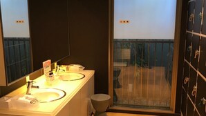 Une salle de bain moderne avec deux lavabos, un grand miroir et une porte en verre donnant sur un balcon.