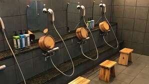 Des toilettes publiques équipées de plusieurs lavabos, de tabourets en bois et de distributeurs de savon.