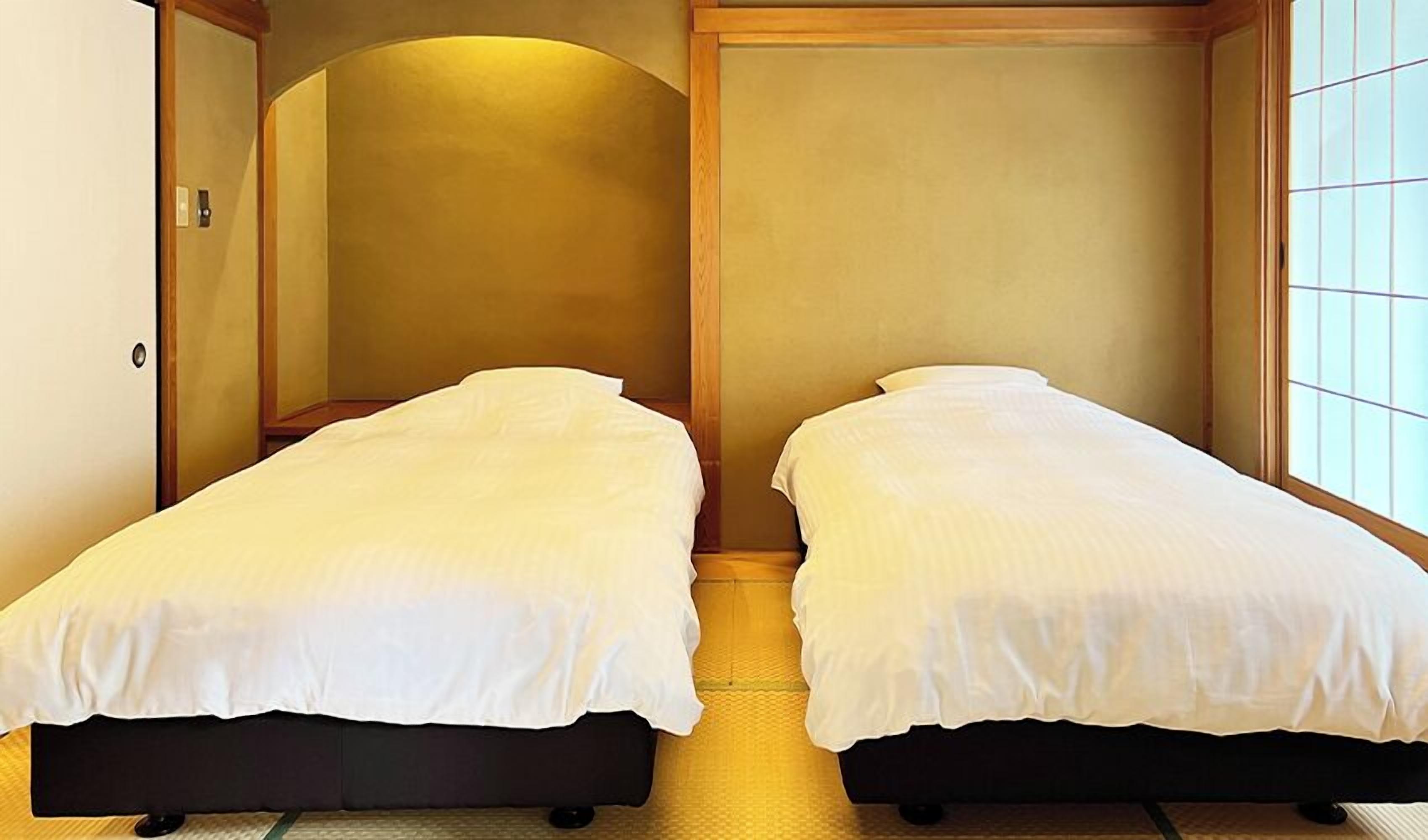 Une chambre avec deux lits simples, des murs en bois et une fenêtre à carreaux.