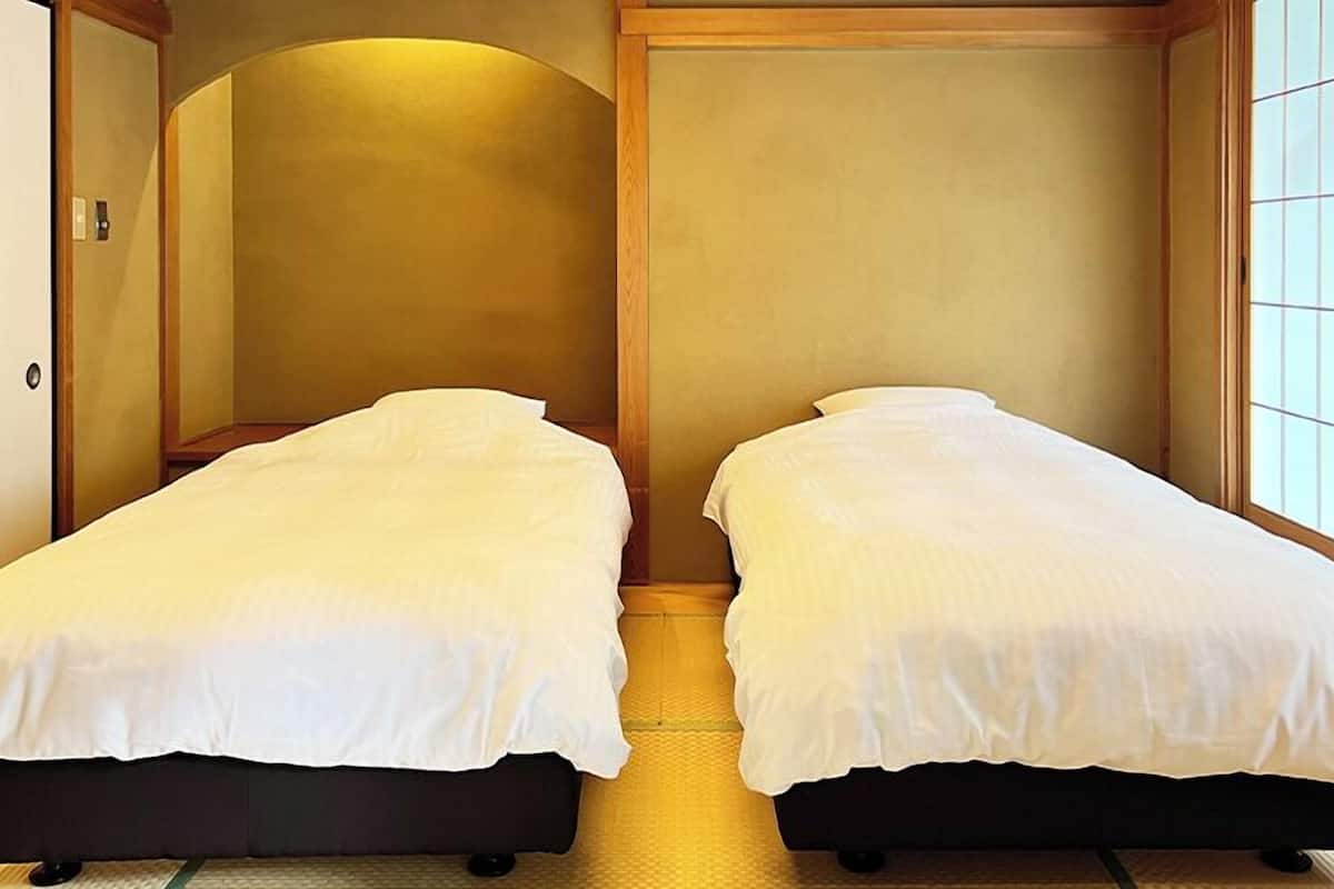 Une chambre avec deux lits simples, des murs en bois et une fenêtre à carreaux.