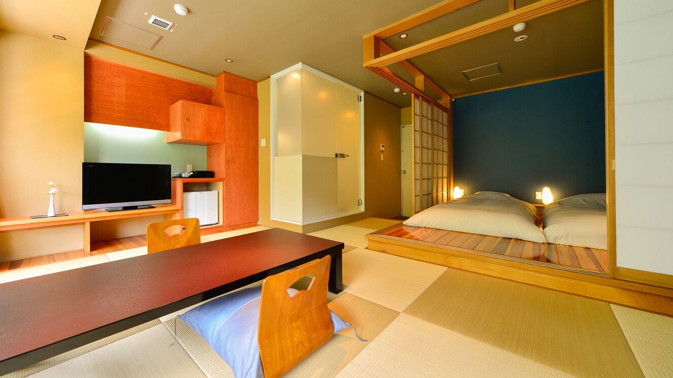 Une pièce de style japonais traditionnel, avec un sol recouvert de tatamis, une table basse, un téléviseur et un lit équipé de matelas futon.