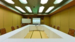Une salle de conférence équipée d’une longue table, de chaises, d’un écran de projection et d’un écran de présentation.