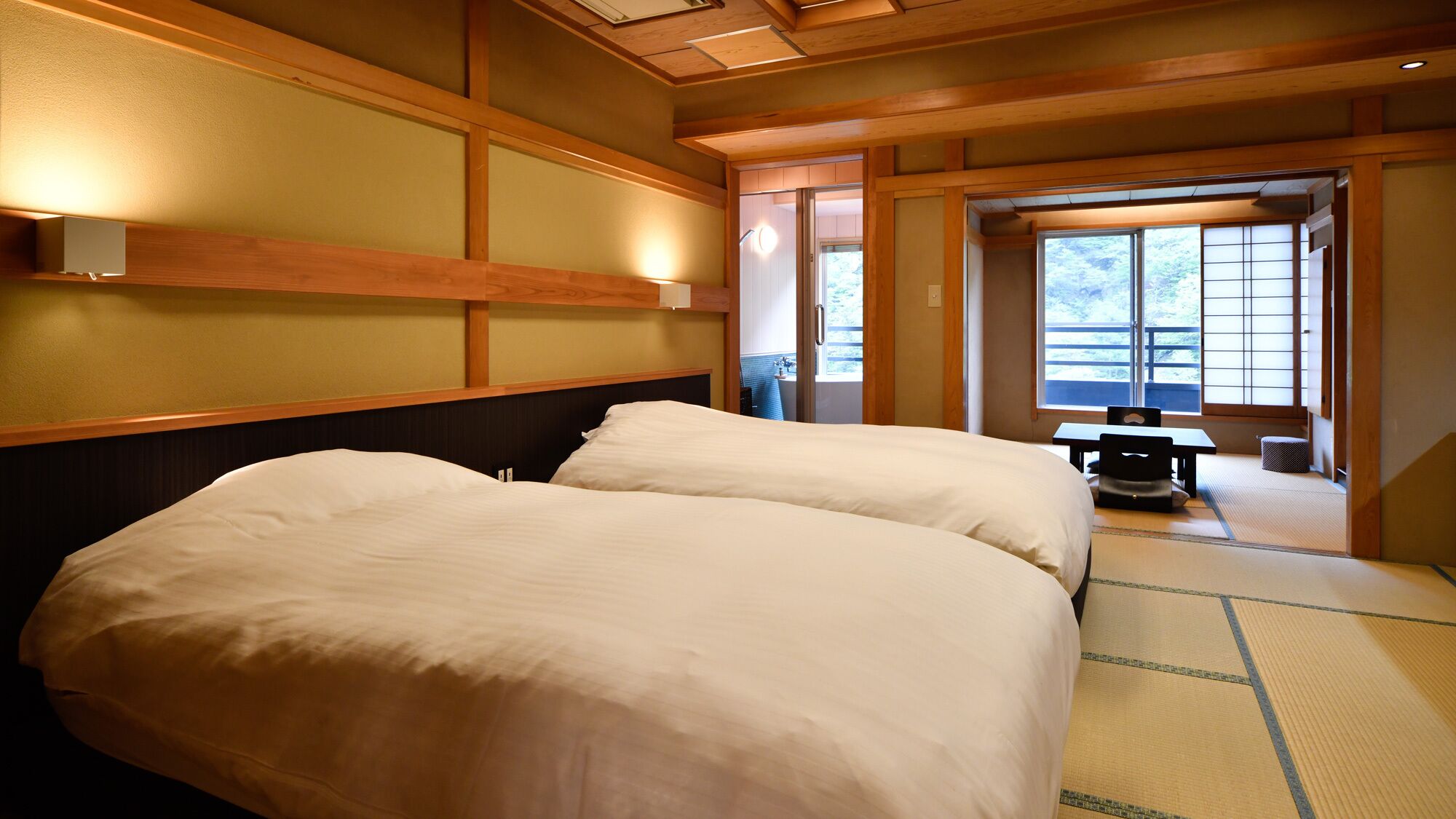 Une chambre d’hôtel avec deux lits, une petite table et une vue sur l’extérieur grâce à une porte coulissante.