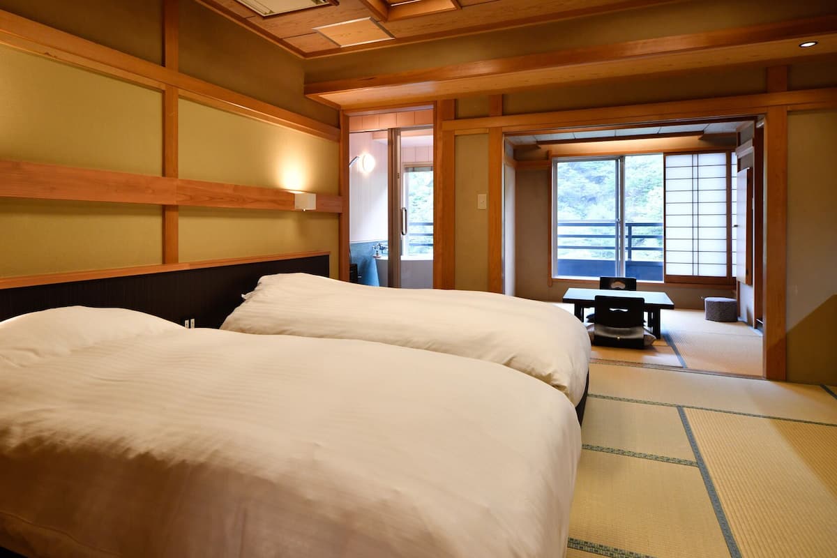 Une chambre d’hôtel avec deux lits, une petite table et une vue sur l’extérieur grâce à une porte coulissante.