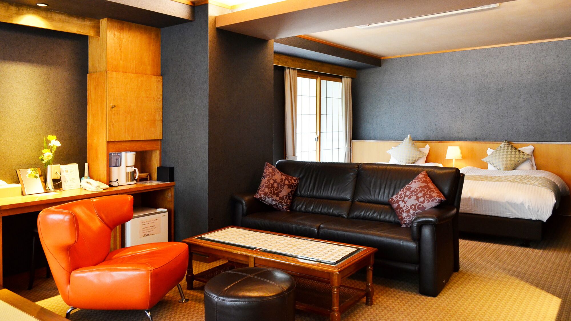 Une chambre d’hôtel avec un canapé en cuir, un bureau en bois, un lit et une fenêtre.