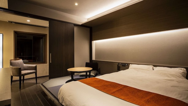 Une chambre d’hôtel moderne avec un grand lit, une petite table ronde, une chaise et une fenêtre.