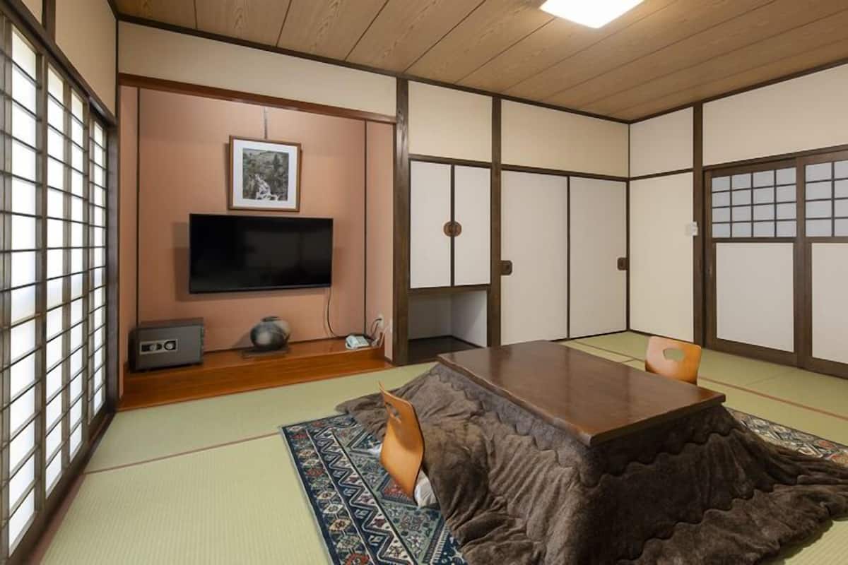 A tatami mat room with a television, a cabinet, and a traditional Japanese sliding door.