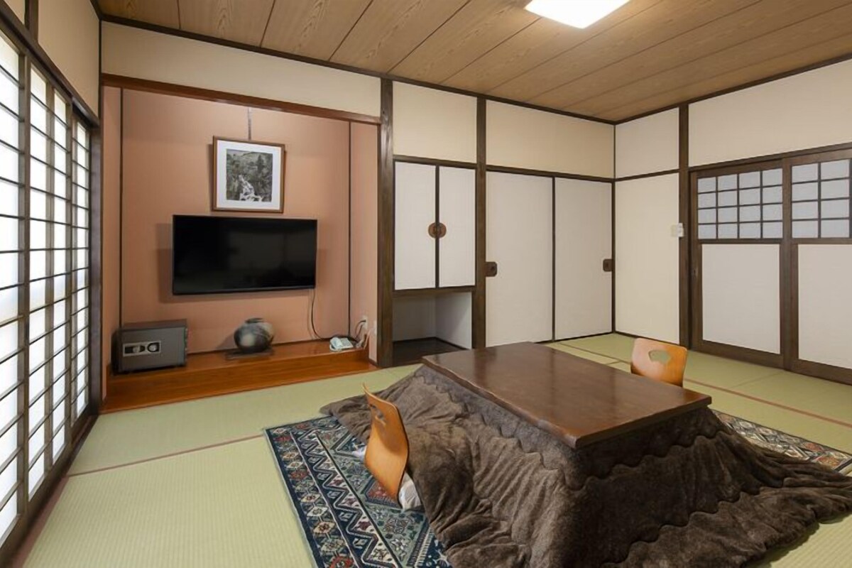 A tatami mat room with a television, a cabinet, and a traditional Japanese sliding door.