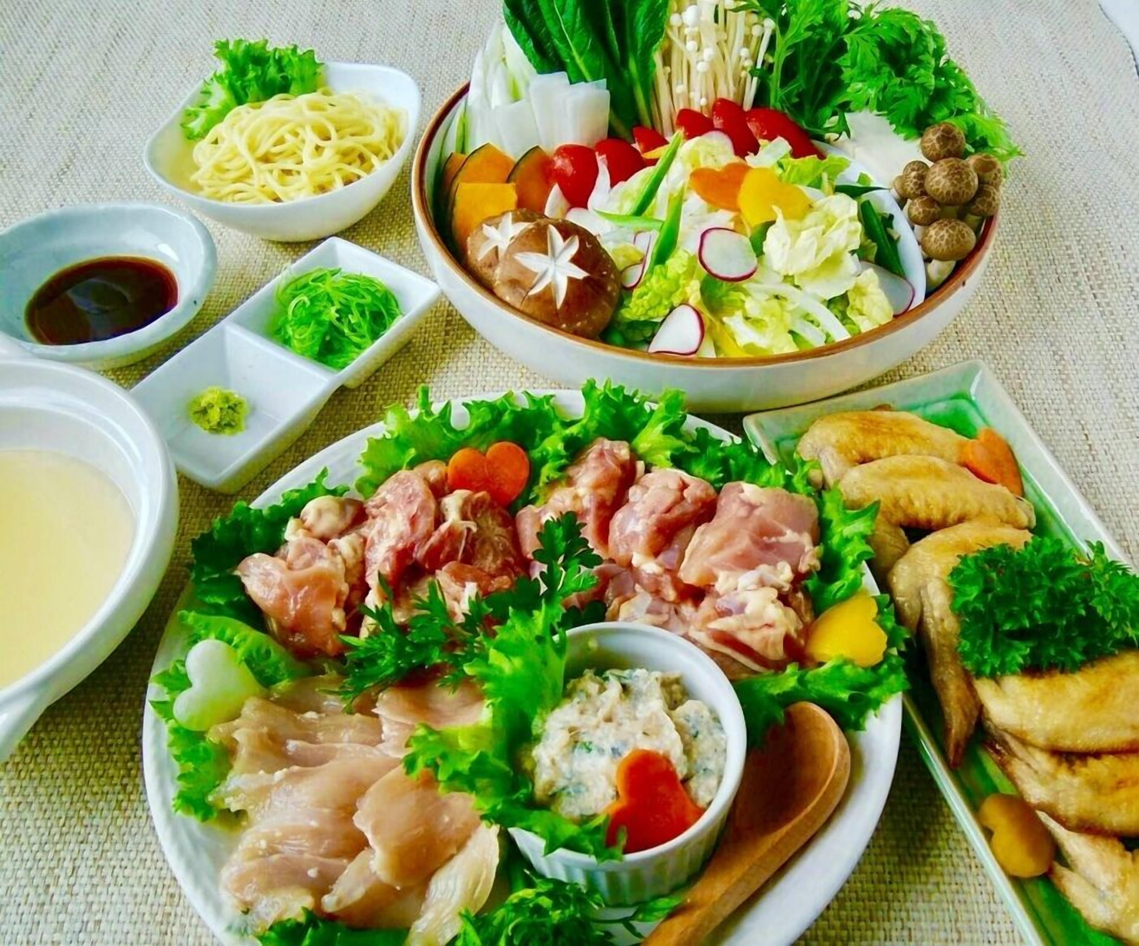 Una varietà di piatti, tra cui noodles, insalate e carni, disposti su un tavolo con piccole ciotole di salse.
