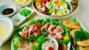 Una varietà di piatti, tra cui noodles, insalate e carni, disposti su un tavolo con piccole ciotole di salse.