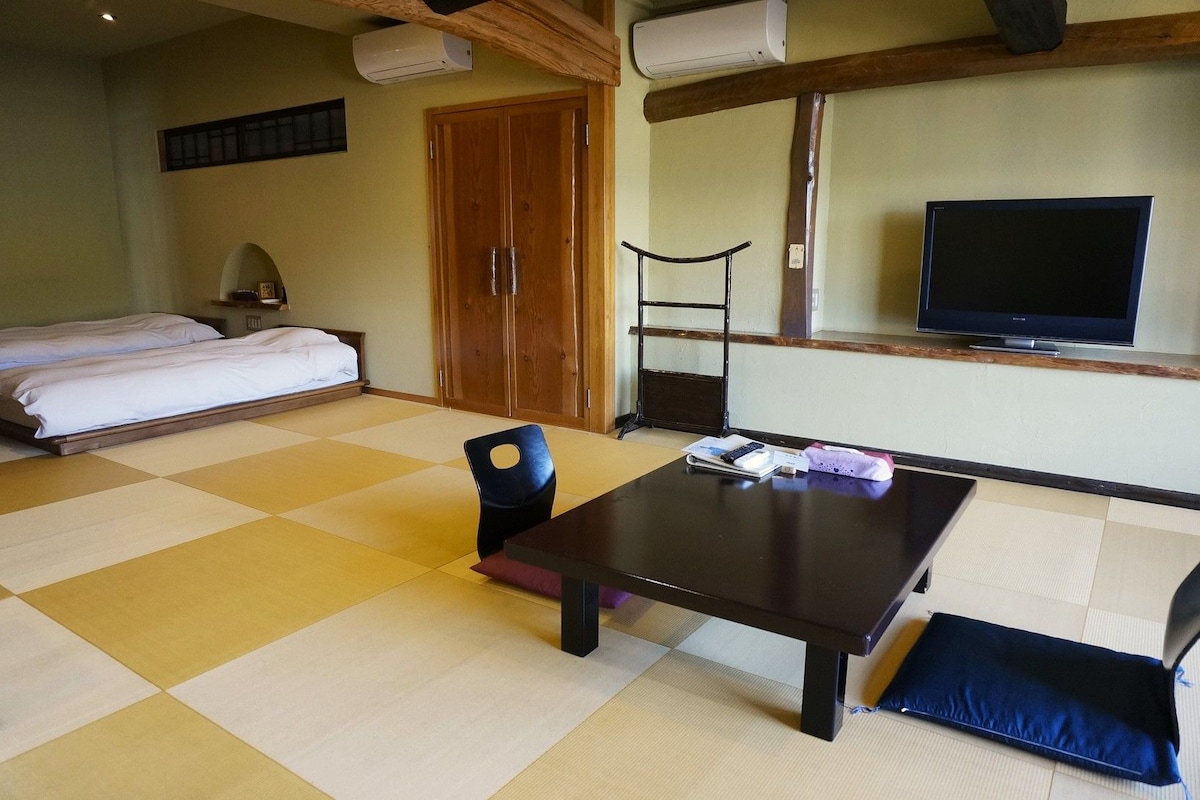 Una habitación con cama, una mesa, una silla, televisor y armario.