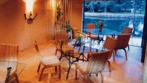 Un comedor con sillas de mimbre, una mesa de vidrio y vista a un cuerpo de agua.