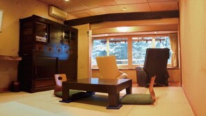 Un cuarto tradicional con esteras de tatami, una mesa baja, un armario y una ventana con vistas a árboles.