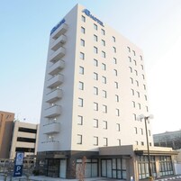 Un edificio de hotel alto de diseño moderno, con varios balcones y un llamativo letrero 'AB Hotel'.