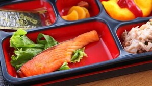 Uma lancheira bento com diversos alimentos, incluindo salmão, arroz e vegetais.
