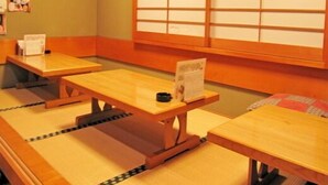 Um quarto japonês tradicional com piso de esteiras de tatame, mesas de madeira e painéis shoji.