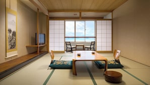 A traditional Japanese room with tatami flooring, a low wooden table, and a view of the sea through shoji screens.