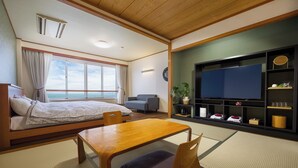 A room with a bed, a TV, a sofa, and a view of the sea.