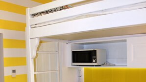 Una kitchenette compacta equipada con microondas, cafetera y un refrigerador pequeño.